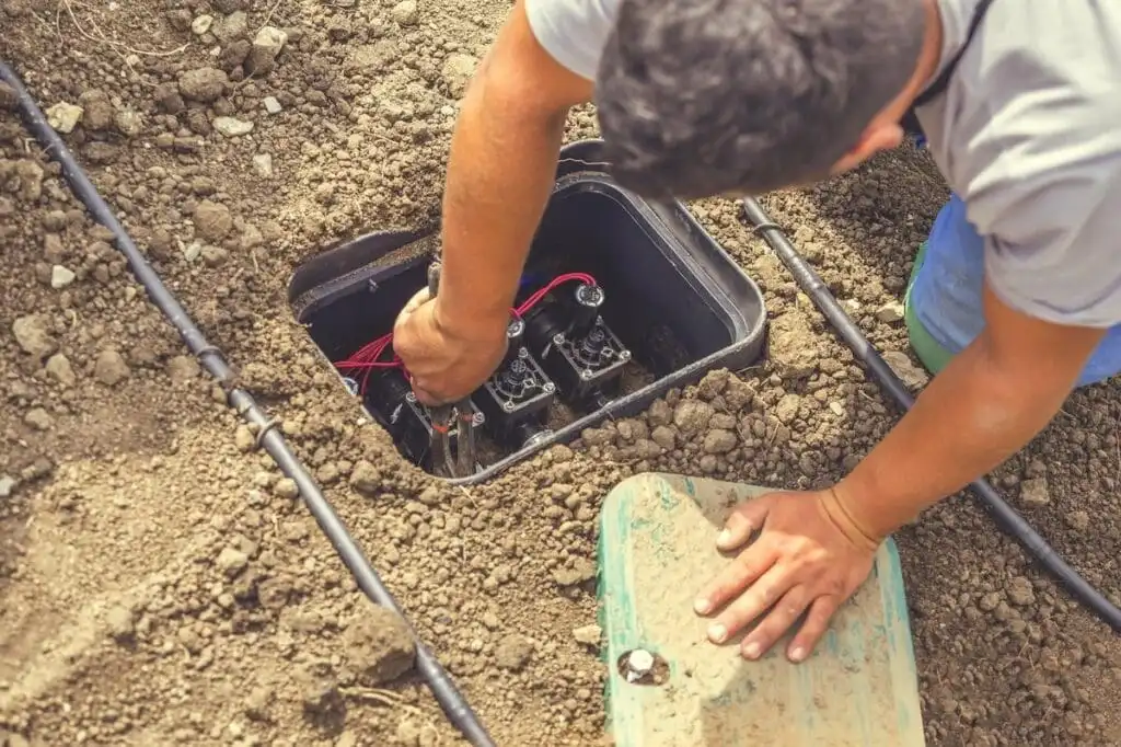 Irrigation technician servicing zone valves inside a valve box