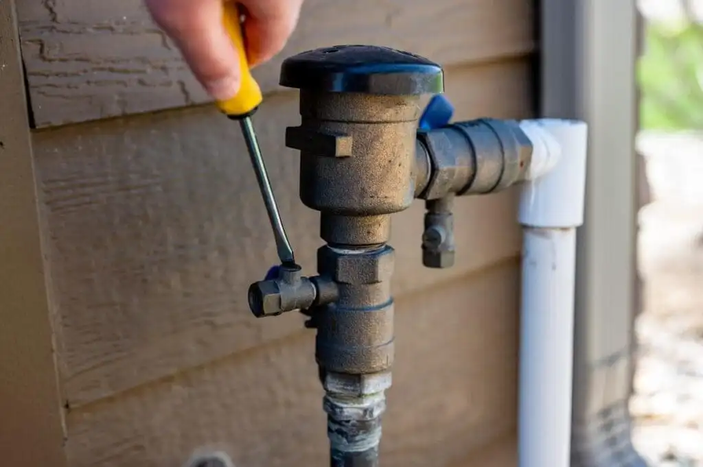 Irrigation supply pipe and backflow preventer assembly exposed above grade during winterization