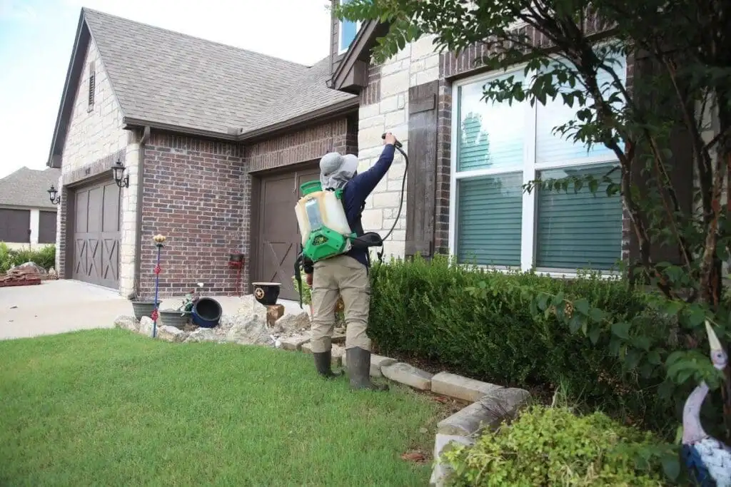 A Complete Lawn Care pest control technician treating foundation and landscape areas at a Broken Arrow home