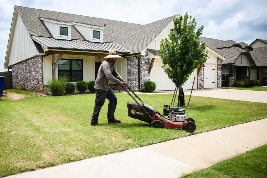 Complete Lawn Care crew member working a Tulsa-area front yard with a commercial Exmark mower