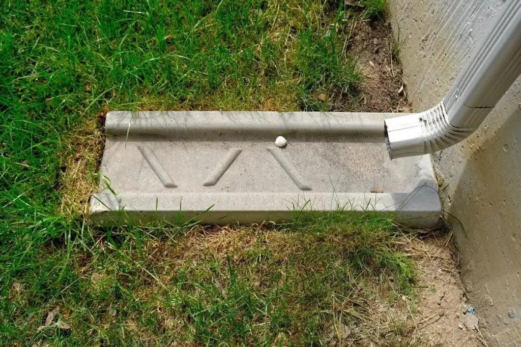Concrete splash block at a downspout discharge on a Tulsa-area home
