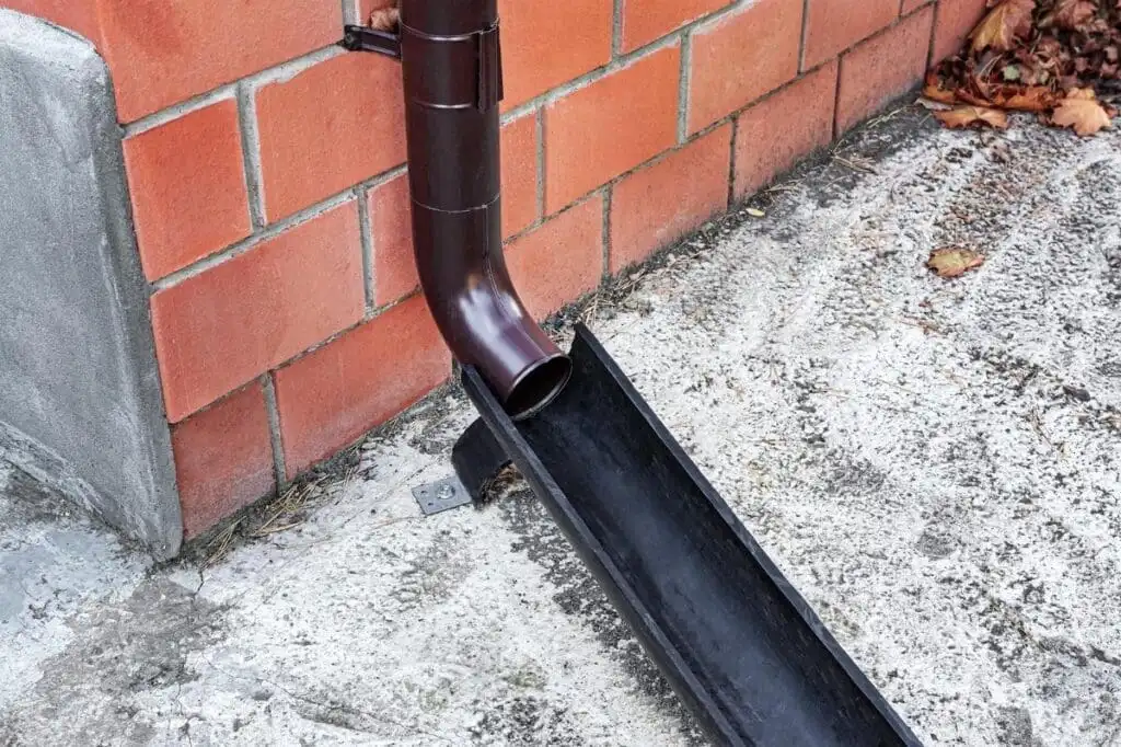 Downspout extender directing water along a hard surface away from the foundation