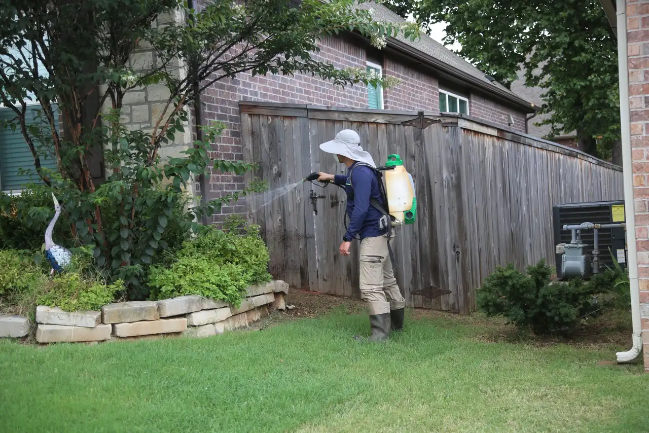 Professional mosquito barrier treatment being applied to harborage zones on a Tulsa metro property