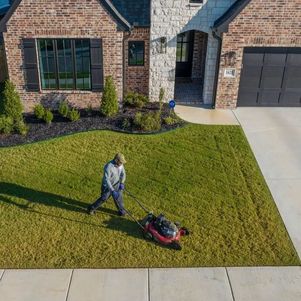 Complete Lawn Care technician mowing a residential front lawn