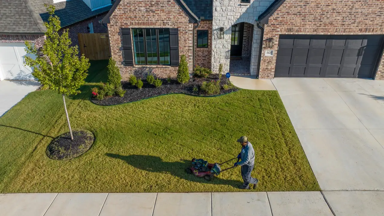 Walk-behind mowing along a landscaped bed by Complete Lawn Care
