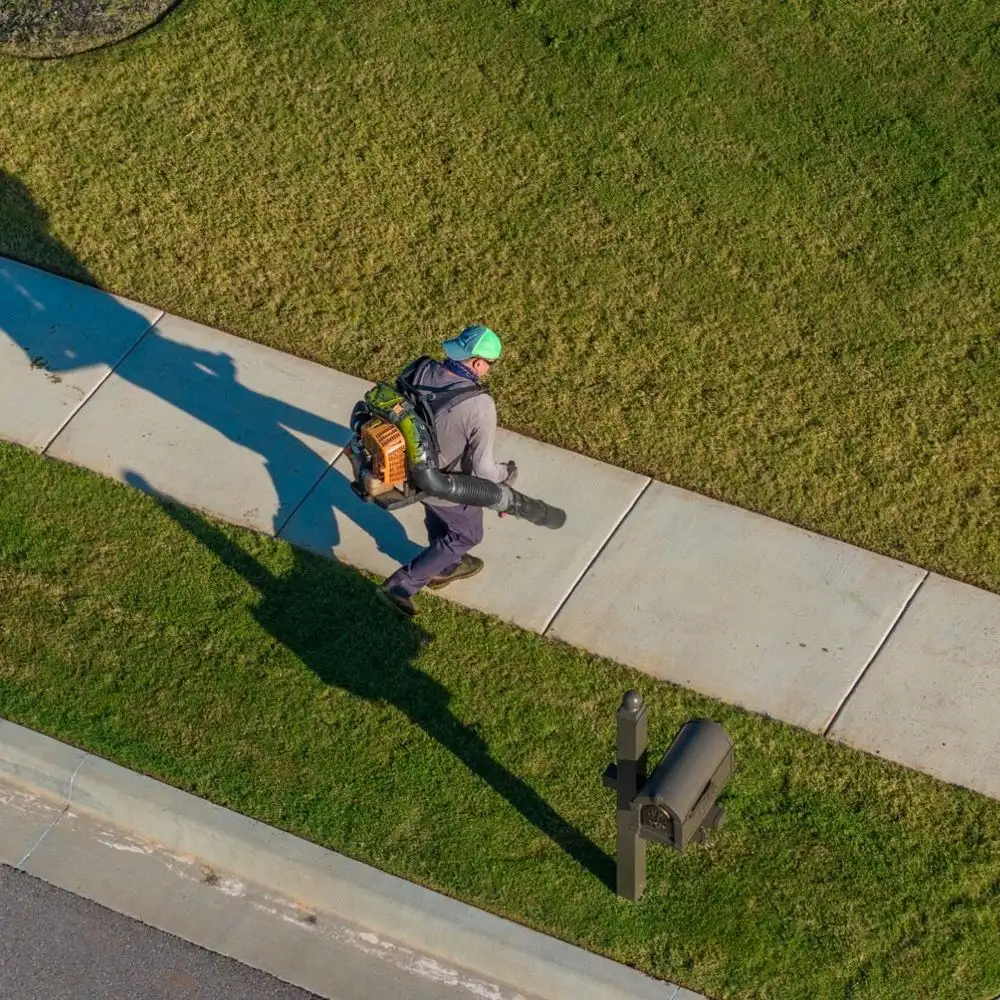 Blowing clippings off the sidewalk after mowing